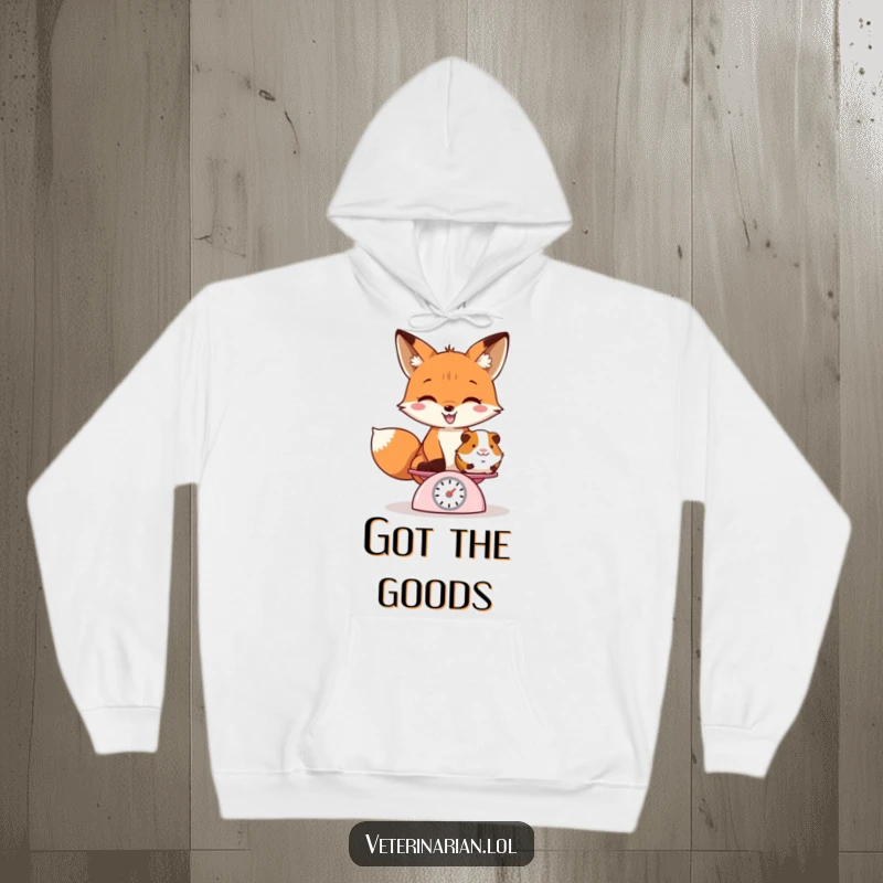 Funny hoodie showing a playful fox with a grin weighing a guinea pig on a tiny scale, embodying gentle mischief.
